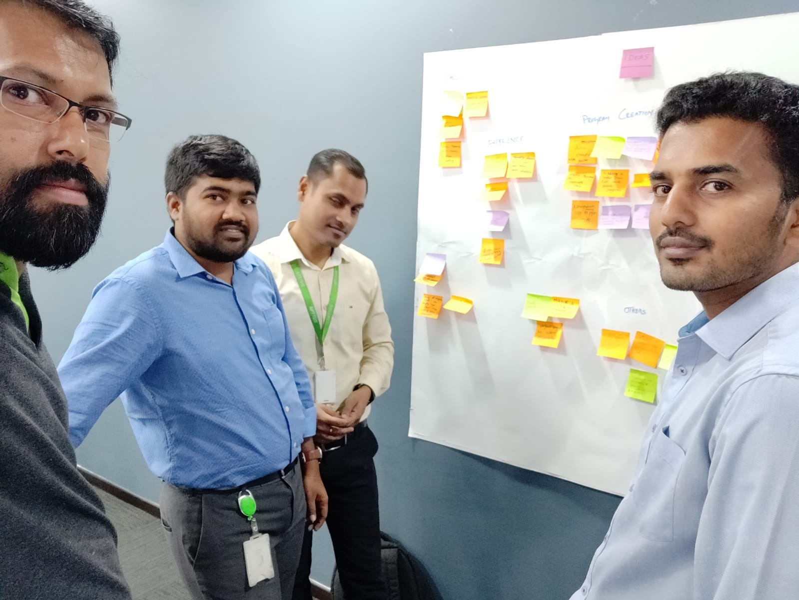 Photo of the Apttus India UX team gathered around the whiteboard.